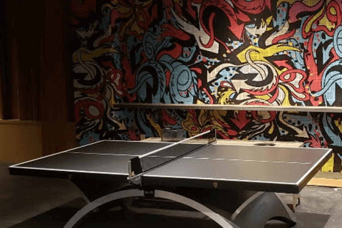 Guests around a Space Ping Pong table under neon venue lighting
